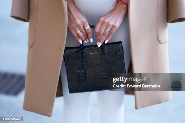 Patricia Gloria Contreras wears a beige coat, a white jumpsuit, a black leather bag from Saint Laurent, during a street style fashion photo session,...