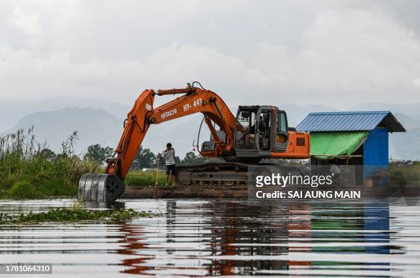 This photo taken on October 18, 2023 shows an excavator being used to clear a floating island on Inle Lake in southern Shan State. Floating farms...