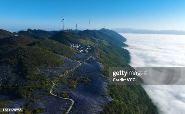 Aerial view of wind turbines and solar panels at a wind and solar hybrid power generation plant on a mountain on October 30, 2023 in Chongqing, China.