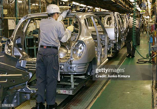 Workers assmble Daihatsu cars at the Shiga plant February 12, 2003 in Shiga, Japan. Daihatsu Motor Co., Ltd. Rolled out the prototypes of hybrid cars...