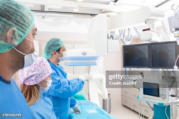 team of doctors performing angiography operation in a modern hospital. operating room. - arteriogram stock pictures, royalty-free photos & images