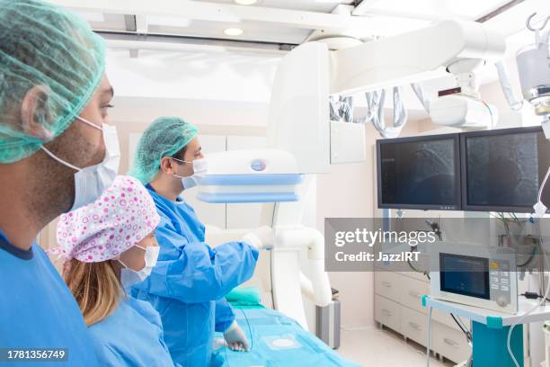 team of doctors performing angiography operation in a modern hospital. operating room. - aneurysm stock pictures, royalty-free photos & images