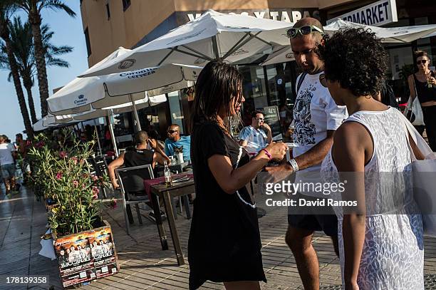 Club promotions girl issues an entrance bracelet to a customer on August 22, 2013 in Ibiza, Spain. The small island of Ibiza lies within the...