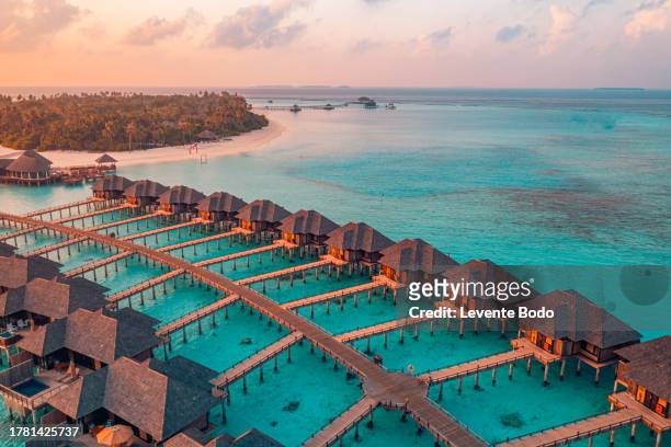 amazing aerial beach landscape. beautiful maldives sunset seascape view. horizon colorful sea sky clouds over water villa pier pathway. tranquil drone view island lagoon tourism travel exotic vacation - return to paradise stock pictures, royalty-free photos & images