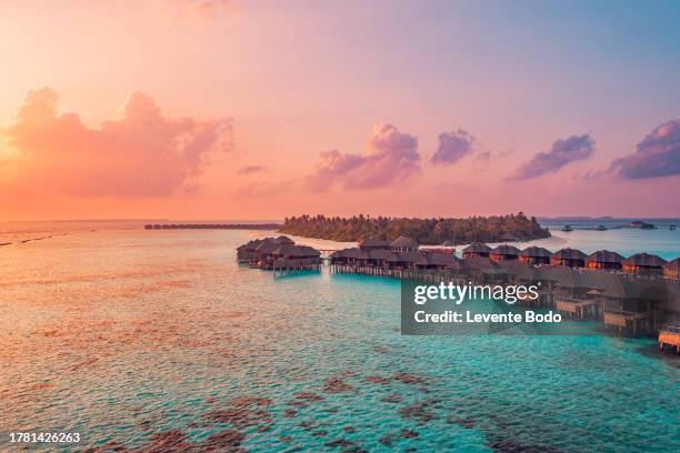 amazing aerial beach landscape. beautiful maldives sunset seascape view. horizon colorful sea sky clouds over water villa pier pathway. tranquil drone view island lagoon tourism travel exotic vacation - maldives stock pictures, royalty-free photos & images