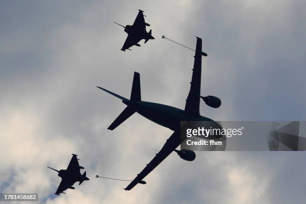 silhouette of a military aircraft tanker with two fighter jets in the sky - military convoy stock pictures, royalty-free photos & images