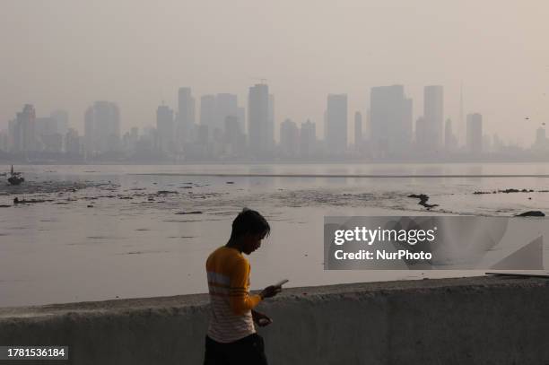 Man walks at a park as heavy smog covers the high rise buildings in Mumbai, India, on 13 November, 2023.