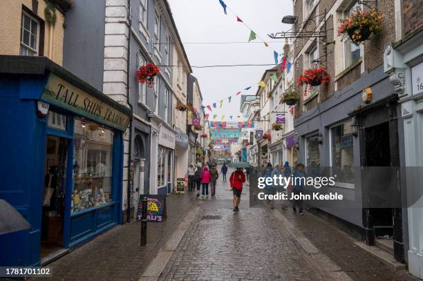 People walk along the street past shops on an overcast wet day on September 20, 2023 in Falmouth, England.