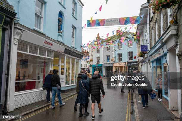 People walk along the street past shops on an overcast wet day on September 20, 2023 in Falmouth, England.