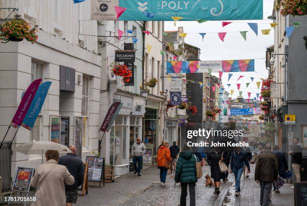 People walk along the street past shops on an overcast wet day on September 20, 2023 in Falmouth, England.