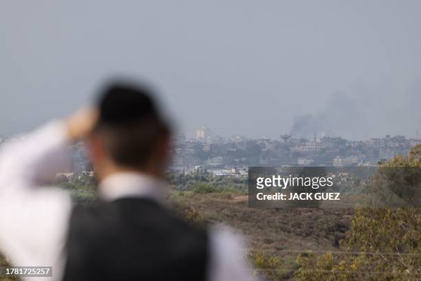 This picture taken from a position along the border with the Gaza Strip in southern Israel shows an ultra-Orthodox jewish man watching ongoing...