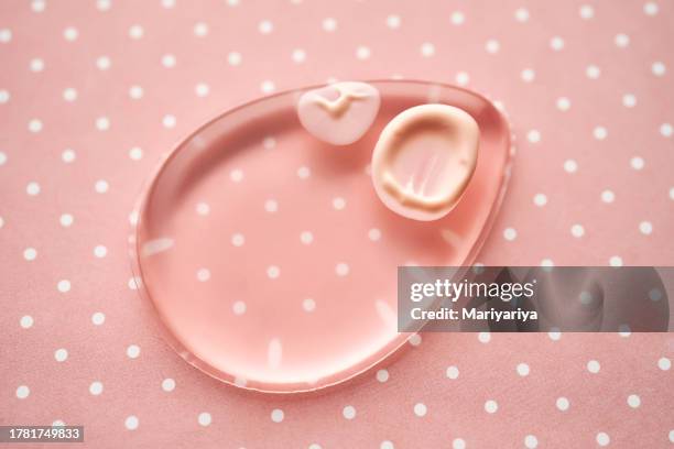 silicone sponge for applying makeup on a pink background with polka dots. - makeup sponge stock pictures, royalty-free photos & images