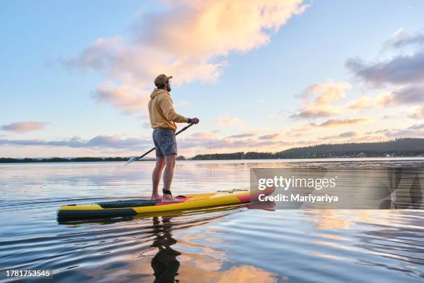 a young korean man on a paddleboard at sunset. - paddleboard stock pictures, royalty-free photos & images