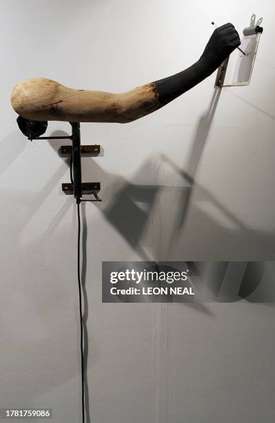 Mechanised wooden arm by artist Tim Lewis writes on a postcard at the Kinetica Art Fair in London on February 27, 2009. The event is the UK's first...