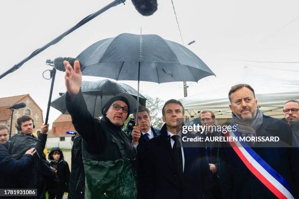 France's President Emmanuel Macron listens to explanations of a farmer during a visit in Le Doulac near Saint-Omer, northern France on November 14 as...