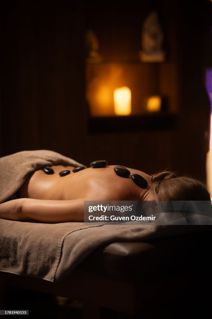 Beautiful young woman relaxing in spa salon with hot stone massage on body, Beauty treatment therapy, a woman getting a hot stone massage at a spa,Beautiful young woman in the spa,Escape from the stresses of every day life