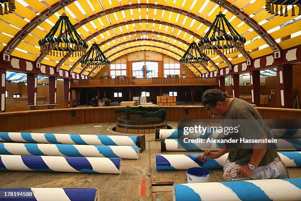 Worker painting Maibaum poles at the Loewenbraeu Festzelt three weeks ahead of Oktoberfest on August 27, 2013 in Munich, Germany. Munich Oktoberfest,...