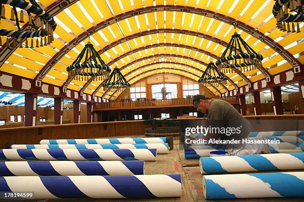 Worker painting Maibaum poles at the Loewenbraeu Festzelt three weeks ahead of Oktoberfest on August 27, 2013 in Munich, Germany. Munich Oktoberfest,...