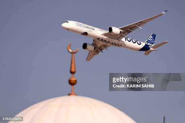 An Airbus A350-1000 aircraft flies above a mosque during the 2023 Dubai Airshow at Dubai World Central - Al-Maktoum International Airport on November...
