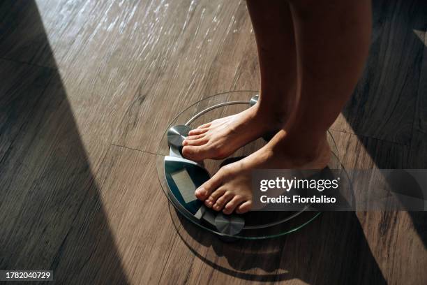 a woman standing in the morning on the scales - waage stock-fotos und bilder