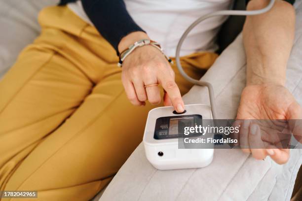 a woman sitting on the sofa - high blood pressure gauge stock pictures, royalty-free photos & images
