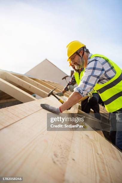 caucasian roofers, using nails and hammer while making a roof beam - roof inspector stock pictures, royalty-free photos & images