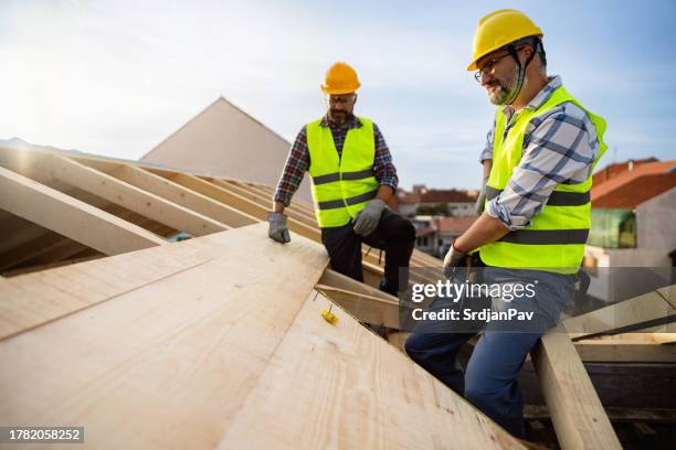 mid-adult caucasian male roofers making an roof beam - dakdekker stockfoto's en -beelden