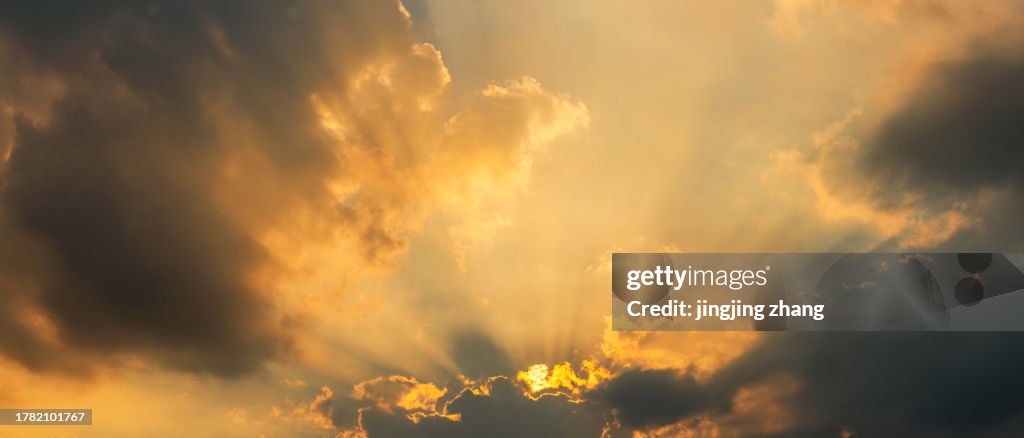 In the evening, dark clouds illuminated by sunlight over the city reveal the Tyndall beam