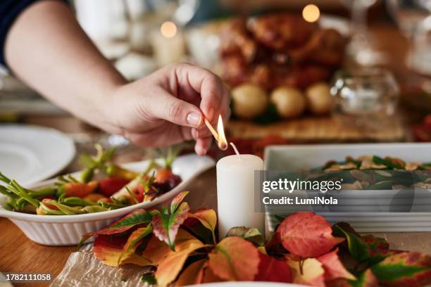 light, candle and hand on table at christmas or thanksgiving dinner, meal or celebration with food. fine dining, buffet or person lighting flame with match for festive decoration and supper in home - christmas party host stock pictures, royalty-free photos & images