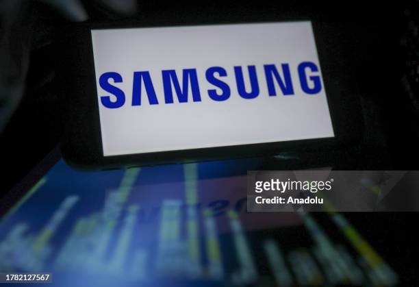 View of the Samsung logo displayed on a smartphone in front of a screen of programming codes in Ankara, Turkiye on November 14, 2023.