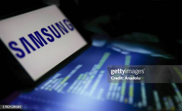 View of the Samsung logo displayed on a smartphone in front of a screen of programming codes in Ankara, Turkiye on November 14, 2023.