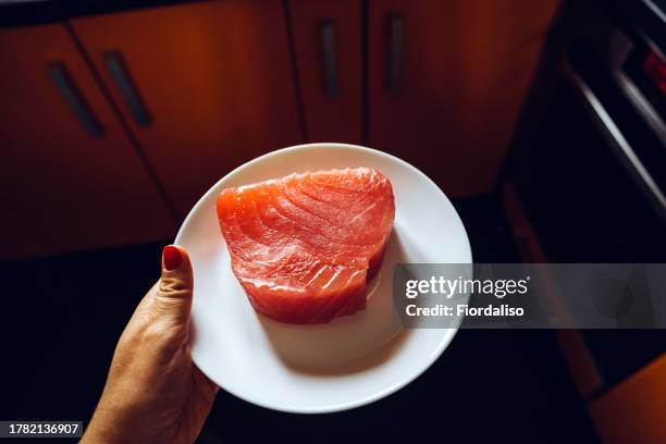 women holding large steak of tuna meat on the plate - tuna foto e immagini stock