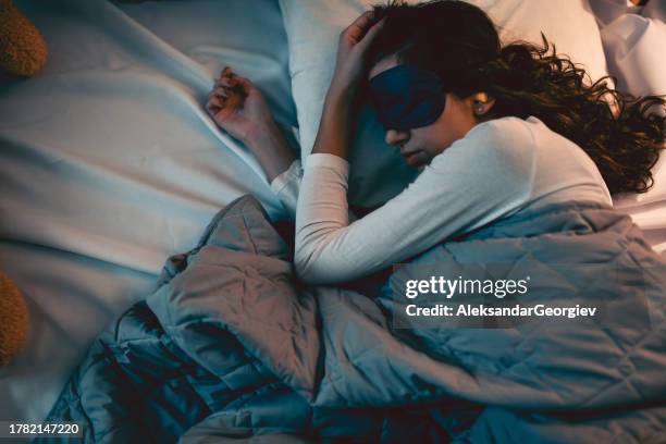 frau ruht sich mit hilfe von schlafmaske und ohrstöpseln gut aus - augenmaske stock-fotos und bilder