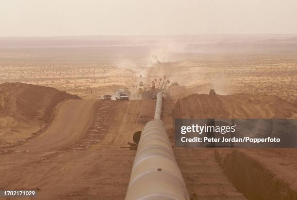 Construction workers use tracked bulldozers to hoist and bury a section of pipework during construction of the Maghreb-Europe Gas Pipeline in the...