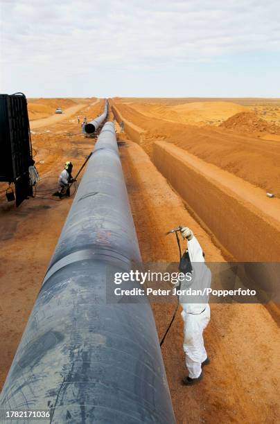 Construction workers seal the joints of pipe sections during construction of the Maghreb-Europe Gas Pipeline in the desert interior of Algeria in...