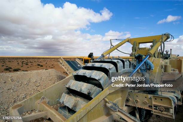 Construction workers dig a trench to bury sections of pipework during construction of the Maghreb-Europe Gas Pipeline in the desert interior of...