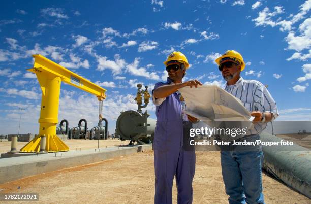 Two expatriate American workers from Bechtel Corporation check plans and blueprints during construction of the Maghreb-Europe Gas Pipeline in the...