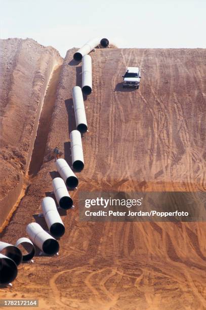Truck drives past sections of pipework waiting to be joined together, sealed and buried during construction of the Maghreb-Europe Gas Pipeline in the...