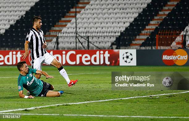 Adam Szalai of Schalke scores his team's first goal as Kostas Katsouranis of PAOK looks on during the UEFA Champions League second leg play-off match...