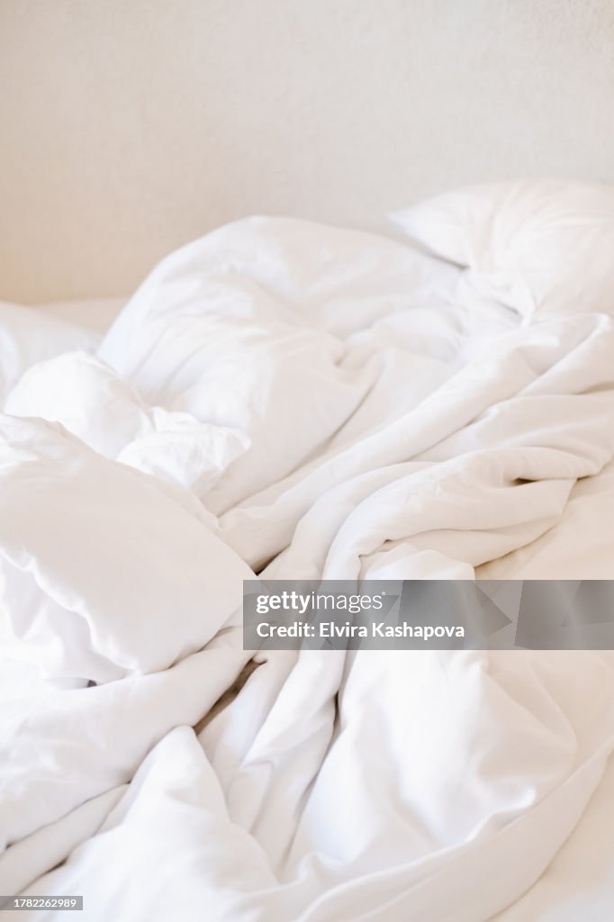 Crumpled white linens on the bed