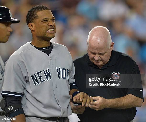 Robinson Cano grimaces as Athletic Trainer Steve Donohue checks out his finger after being hit by a pitch. Cano stayed in the game. Toronto Blue Jays...