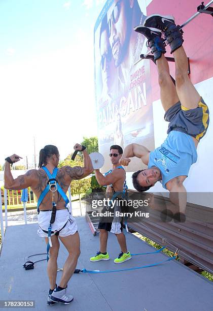 Live body builders work out on a billboard over Sunset Boulevard celebrating the Blu-Ray/DVD release of 'Pain & Gain' on August 27, 2013 in West...