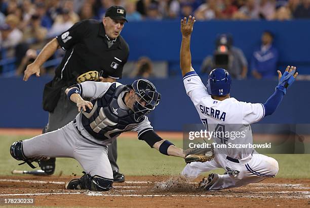 Moises Sierra of the Toronto Blue Jays is tagged out at home plate in the fifth inning during MLB game action as Chris Stewart of the New York...