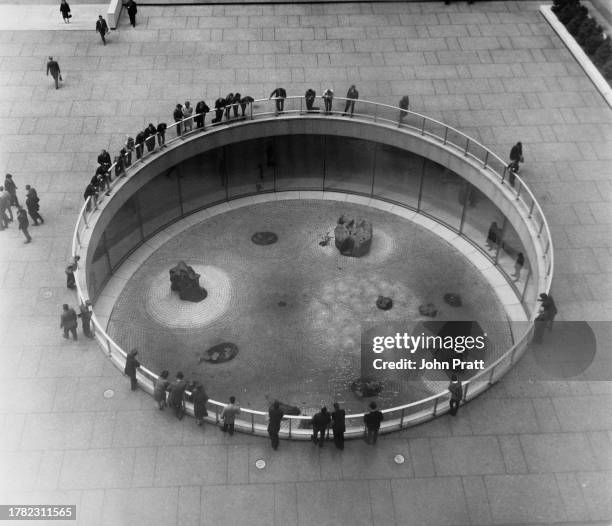 High-angle view of people leaning on the guard rail to inspect the Sunken Garden, by American artist and landscape architect Isamu Noguchi at One...