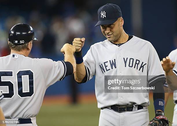 Derek Jeter of the New York Yankees celebrates their victory with first base coach Mick Kelleher during MLB game action against the Toronto Blue Jays...