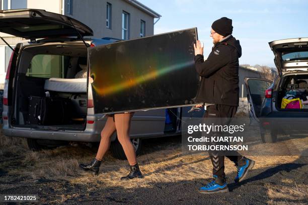 This photo taken on November 13, 2023 shows inhabitants carrying belongings from their homes to a vehicle in Grindavik, southwestern Iceland,...