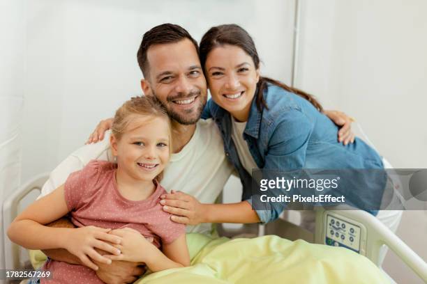happy family looking at camera at hospital ward - icu ward stock pictures, royalty-free photos & images