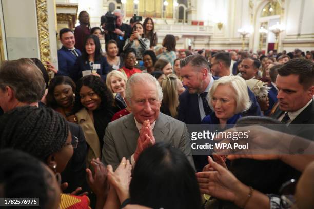 Britain's King Charles III speaks with guests as he meets nurses and midwives to celebrate their work, at Buckingham Palace on November 14, 2023 in...