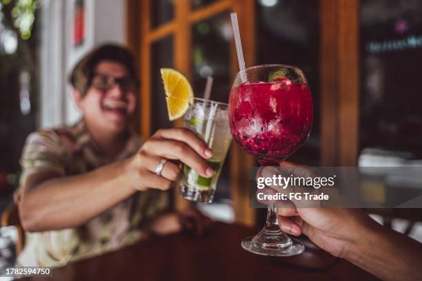 primo piano di una coppia gay sul brindisi celebrativo al bar - caipirinha foto e immagini stock