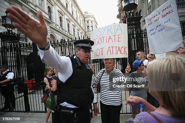 Police officer speaks to protesters gathering on Whitehall outside Downing Street to campaign for no international military intervention in the...